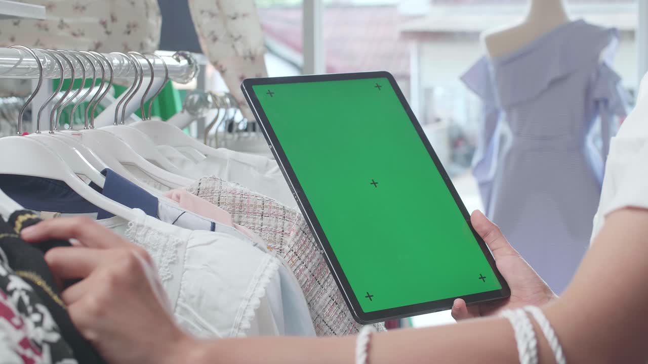Woman shopping with a green screen tablet in a clothing store