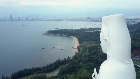 aerial round motion white buddha statue head against hills