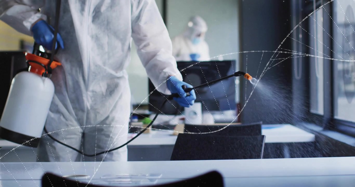 Tecnico della sanificazione che attiva l'ugello e nebulizza disinfettante sulle scrivanie dell'ufficio per una copertura completa
