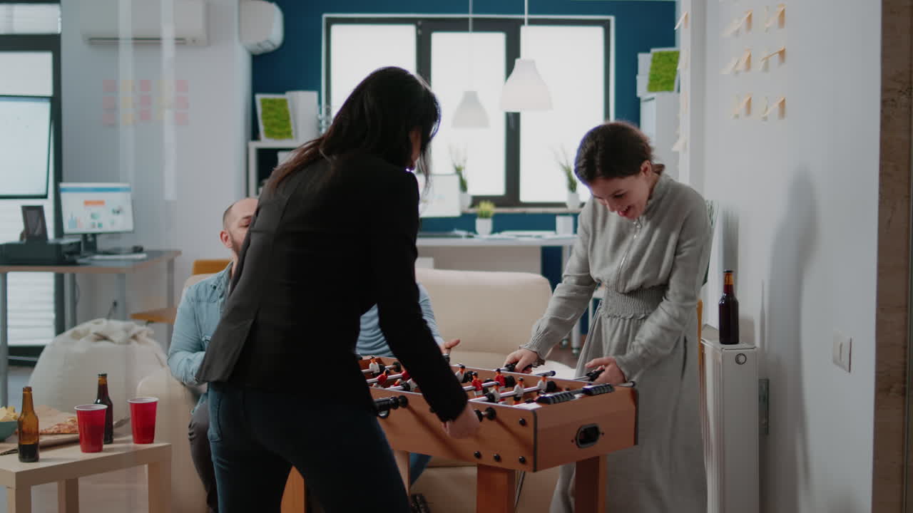 Businesspeople playing foosball game at table to do fun