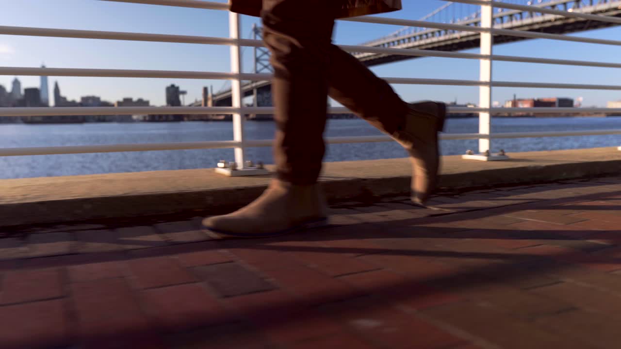 Camden Waterfront Park New Jersey USA - A Well-Dressed Man Walking Smoothly Along The Bay Area Pavement - Wide Shot