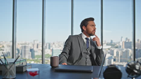 business leader pondering solution at city view. successful banker resting chair