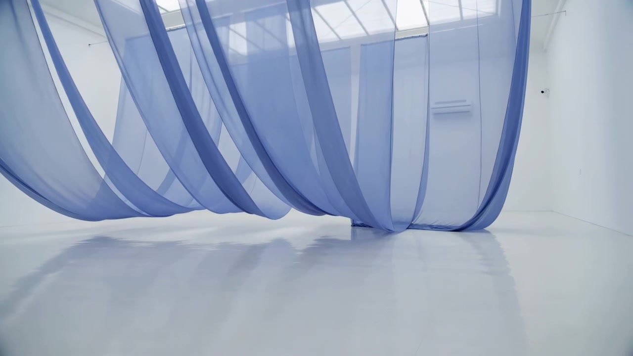 Multiple sheer blue fabric panels suspended from ceiling rails billow and sway in bright minimalist interior, creating soft folds, layered translucency, gentle shadows, and subtle reflections above