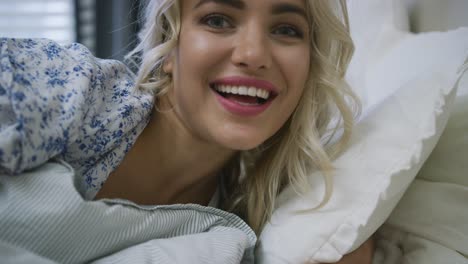 cheerful woman touching camera in bed