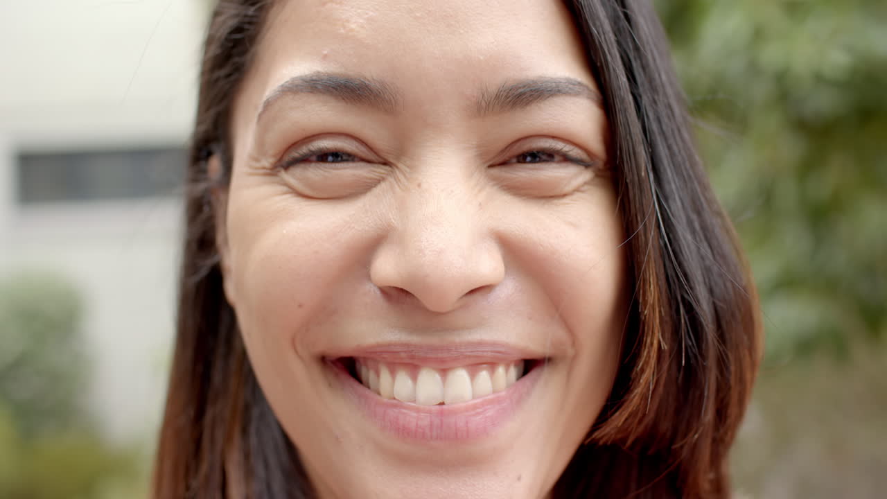 Close-up of a smiling young biracial woman with brown eyes and dark hair