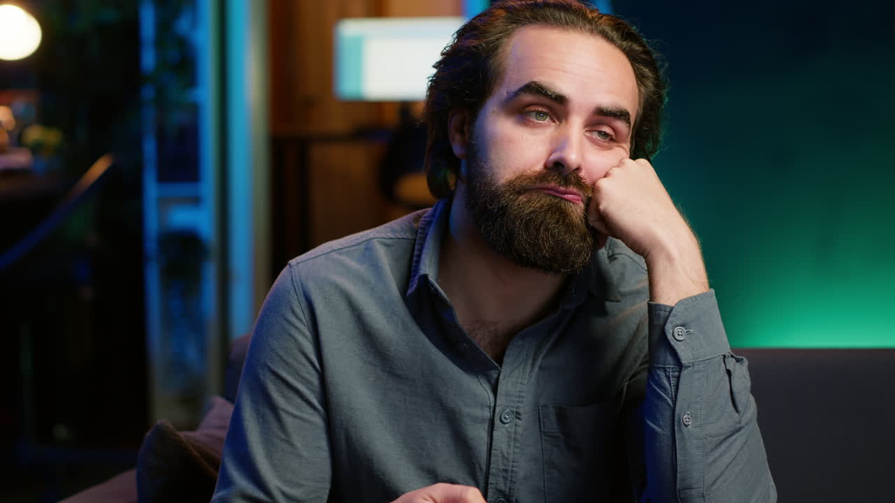 un hombre aburrido sentado en el sofá, volviendo los canales de televisión.