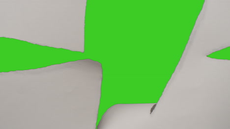 close up of hand tearing off strips of paper uncovering green screen background below