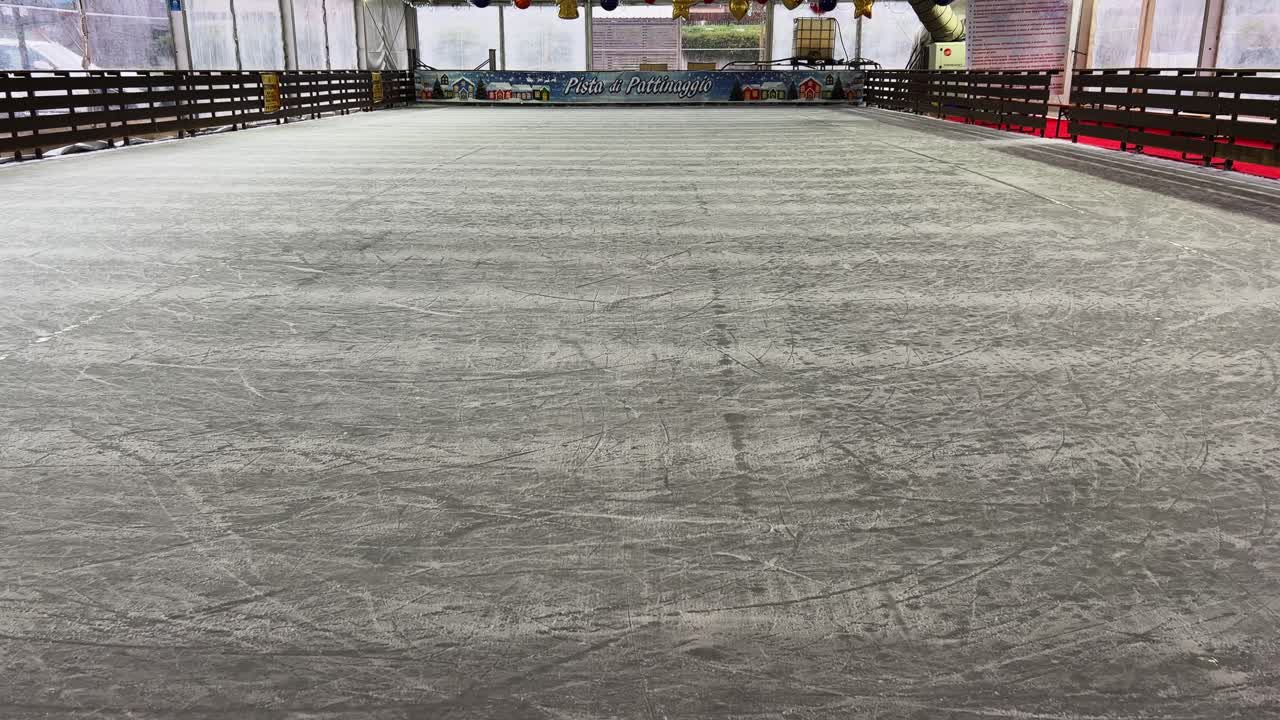 pista de hielo interior vacía y piso congelado para patinar con adornos navideños colgados en el techo