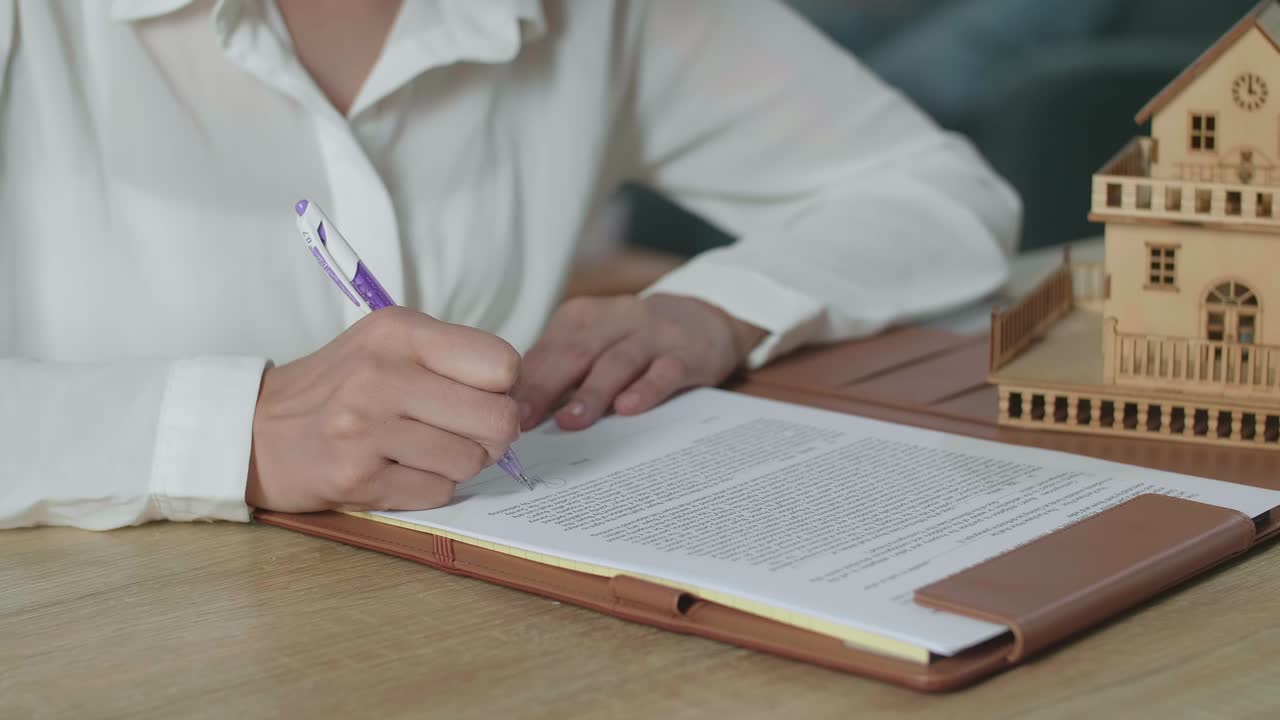 женщина, подписывающая документы о недвижимости
