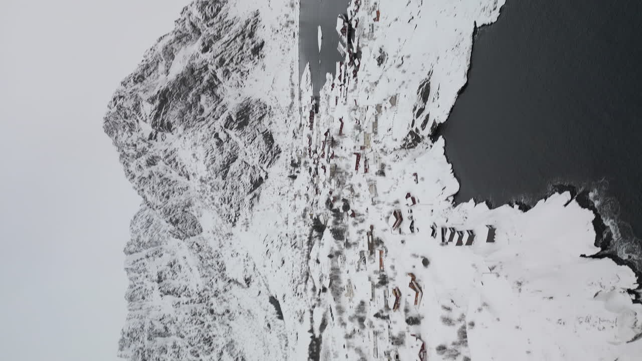 Vertical - Reine Village With Snow-covered Cabins And Mountains In Winter In Norway's Lofoten Islands