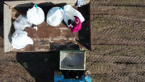 Farmer-use-metal-bucket-to-grab-solid-mineral-fertilizer-and-fill-up-spreader