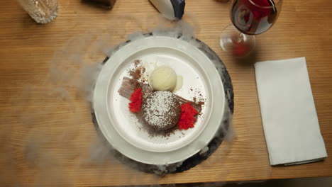 Waiter-serving-dish-lid-with-smoke-in-restaurant-table.-Cloche-opening-in-cafe.