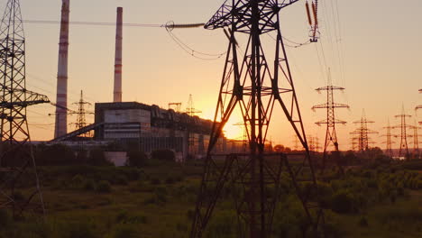 tall voltage tower. distribution and supply electricity at sunset. power electric station with transmission lines against the orange sun. camera rising up.