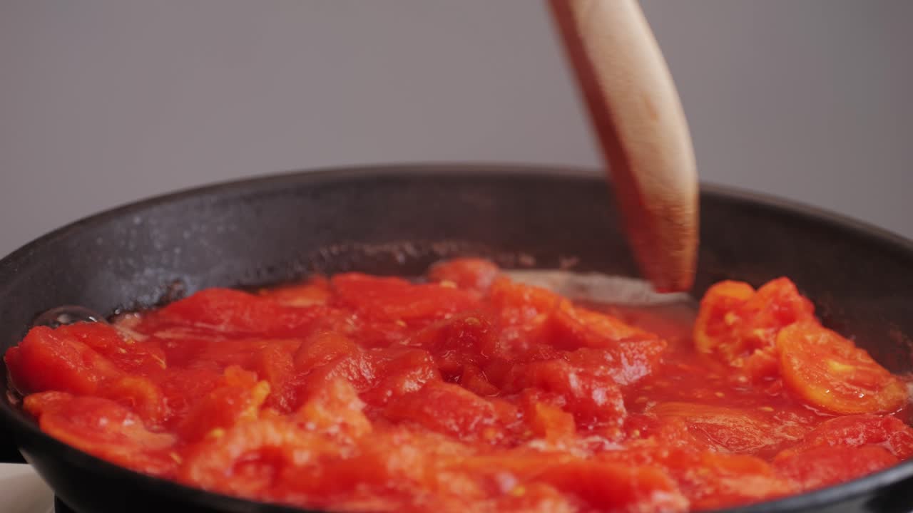 Cooking fresh peeled canned tomato Juice sauce in pan, peeled tomatoes boiling in their own juice, making tomatoes pasta sauce .Top view close up, Italian traditional cuisine food.