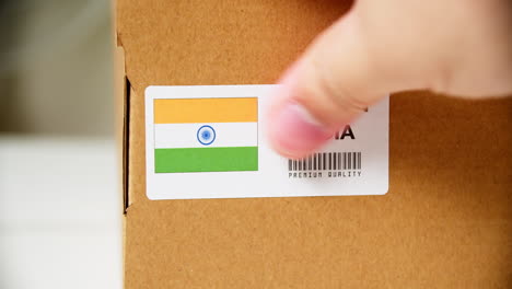 hands applying made in india flag label on a shipping cardboard box with products