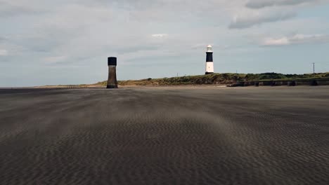 el viento hace olas de arena con dos torres en la distancia