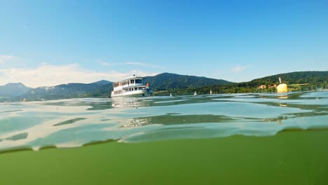 inside the water shot with a one third line under water, a ship is coming and mountains are rounding off the background at a sunny summer day