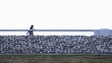 a caucasian male walks energetically on a bridge