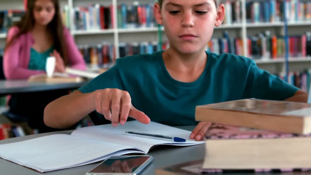 escolar usando el teléfono móvil mientras estudia en la biblioteca