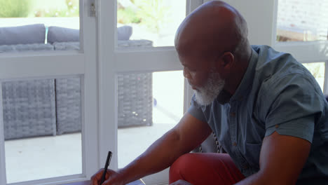 Side-view-of-mature-man-signing-documents-in-living-room-at-home-4k