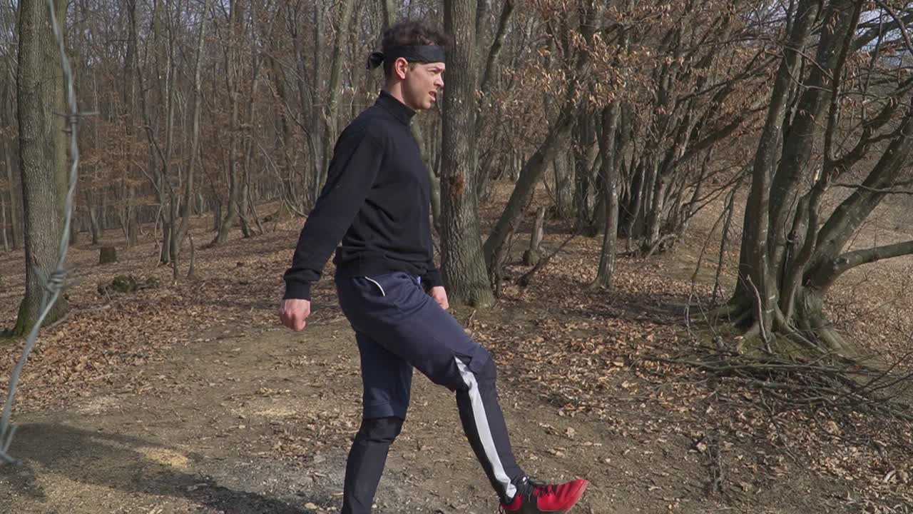 A dynamic outdoor workout in a fall forest, featuring a person balancing on one leg with the other extended backward amid bare trees and dry leaves. Ideal for fitness and sports content.