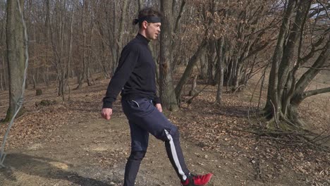 a dynamic outdoor workout in a fall forest, featuring a person balancing on one leg with the other extended backward amid bare trees and dry leaves. ideal for fitness and sports content.