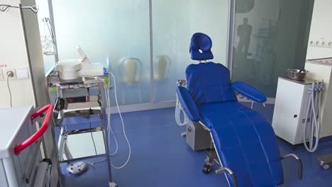 blue comfortable folding chair in dentist's cabinet. light room with diverse equipment for stomatological purposes.