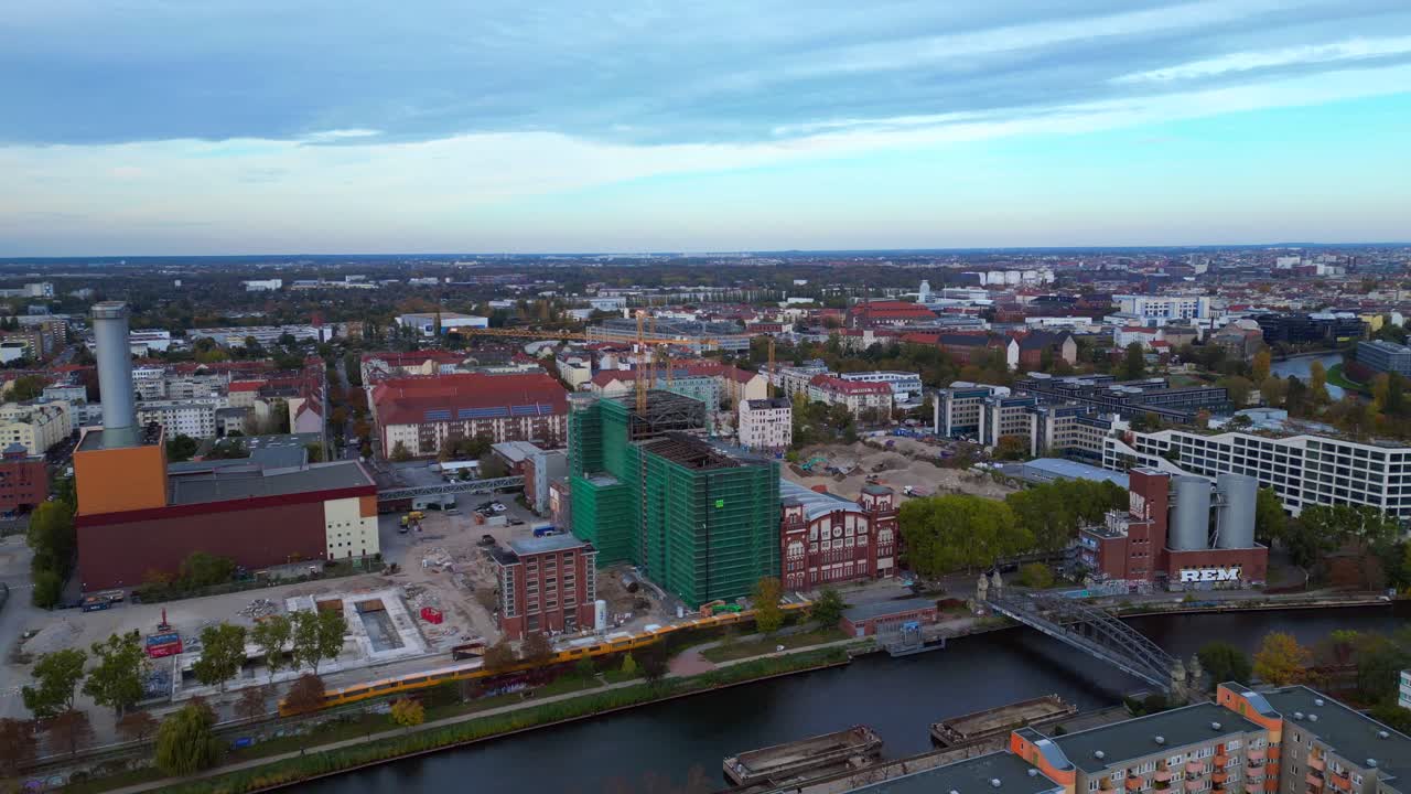 Combined heat and power plant operating in the cityscape by Spree river with new buildings under construction. Best aerial view flight static tripod hovering drone