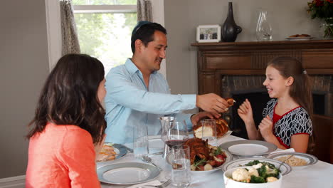 jewish man sharing challah bread with family at shabbat meal