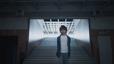 Sad boy walking empty school hall. Teen child going on futuristic stairway.
