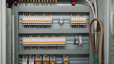 Rows-of-breakers-and-colorful-wires-on-open-circuit-board