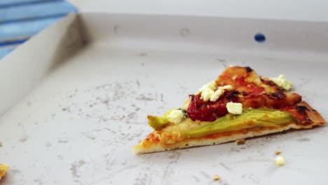 una rebanada de pizza con un bocado faltante en una caja de pizza