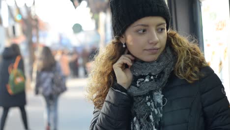 mujer esperando ansiosamente en la calle luciendo preocupada frente a la tienda