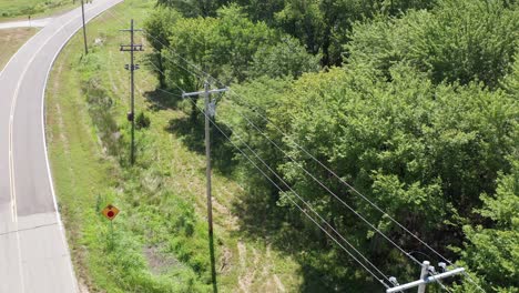 close-up aerial shot flying over a rural utility pole and powerline inspection