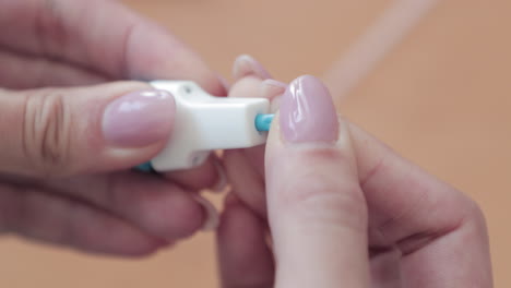 cierre de la mano de una mujer con una lanceta quitando su tapa protectora - kit de prueba casera covid-19 - cámara lenta