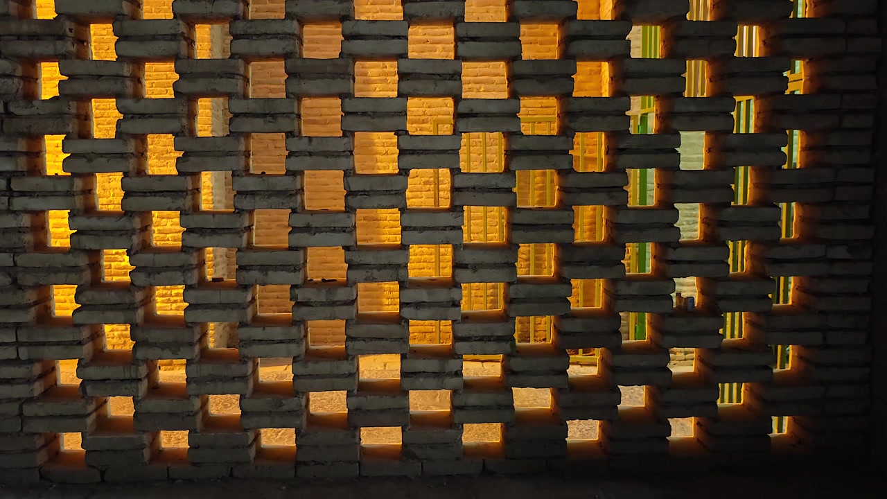 Person Walking Behind a Decorative Brick Wall with Warm Backlighting