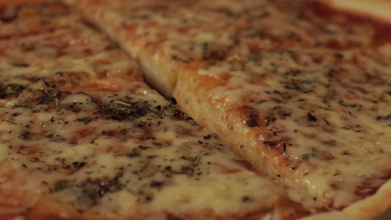 A close-up view of a cheesy pizza with oregano sprinkled on top, capturing the melted goodness and rich texture. Perfect for illustrating delicious homemade or gourmet pizza.