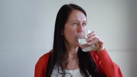 mujer de 50 años bebiendo un vaso de agua