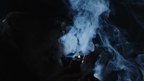 artful dark moody close up portrait: hip backlit man smokes pipe
