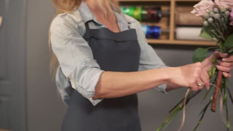 side view of a flower shot assistant tying a bunch of flowers holding them in hands with the ribbon. slow motion shot