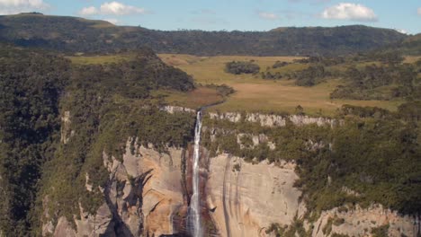 parque nacional chapada dos guimarães, mato grosso, brasil - una impresionante vista del agua que fluye desde la meseta, bajando en cascada por los acantilados de piedra arenisca en cachoeira véu da noiva - toma amplia