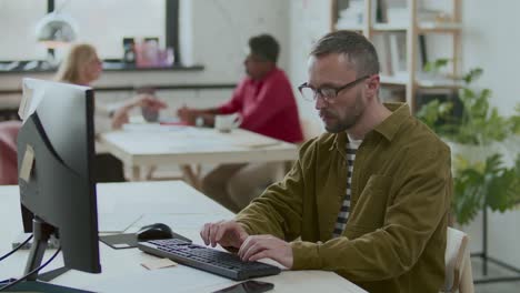 Businessman Working on Computer and Writing on Sticky Note at Office Desk