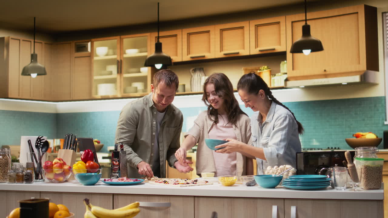 Parents and tween girl laughing while sprinkling mozzarella on pizza