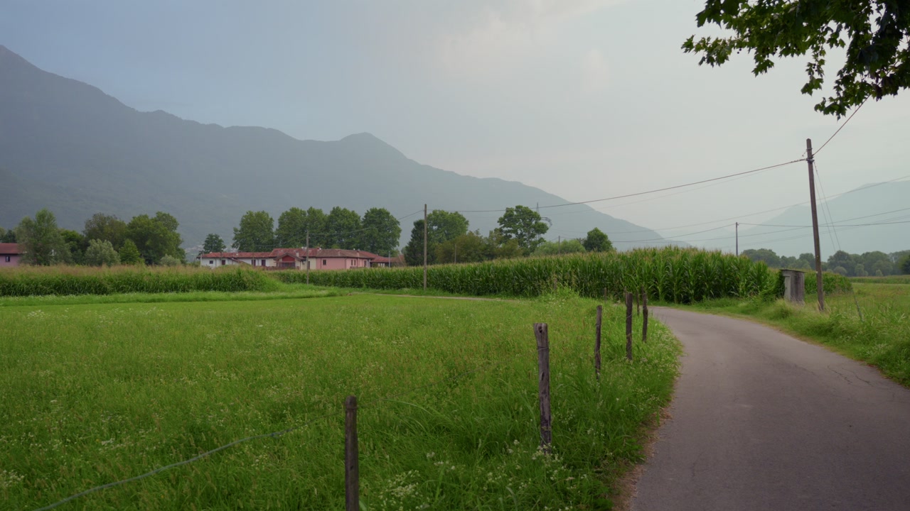 Quiet cycling path winds through green countryside near Lake Como, Italy.