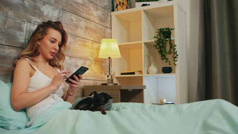 Young-woman-in-pajamas-scrolling-on-her-phone