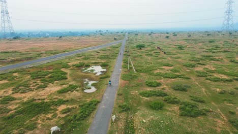 Aerial-Drone-shot-of-kids-cycling-on-a-village-road-of-India