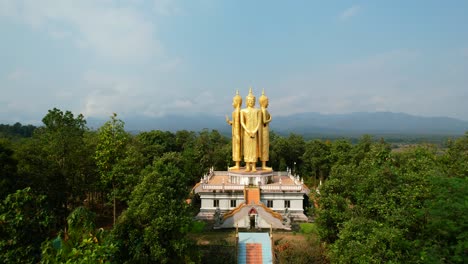 aerial drone of golden wat doi sapanyoo with a large staircase leading to four unique buddha statues located in the mountain hills of chiang mai thailand surround by a forest on a sunny summer day