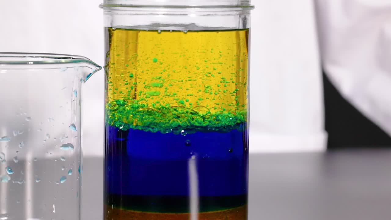 조절된 환경에서 과학적 원리를 보여주는 항아리의 다채로운 층을 보여주는 활기찬 액체 밀도 실험