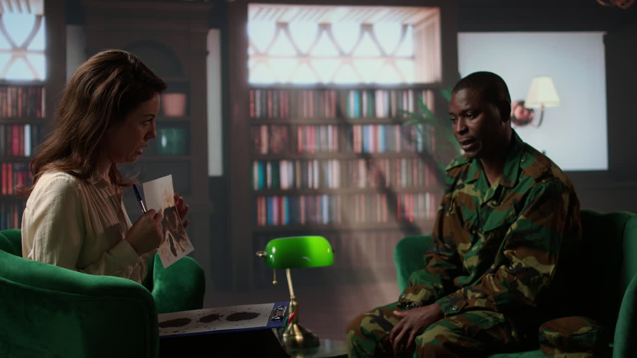 여성 치료사는 유니폼을 입은 흑인 군인에게 로르샤크 잉크블롯 테스트를 제시합니다.