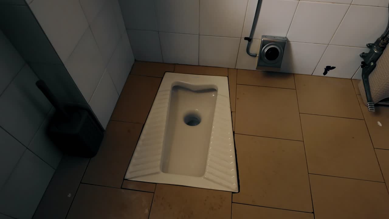 Traditional squat toilet fixture installed in tiled floor of public restroom in Italy
